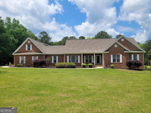 ranch-style house with brick siding, a front yard, and a shingled roof