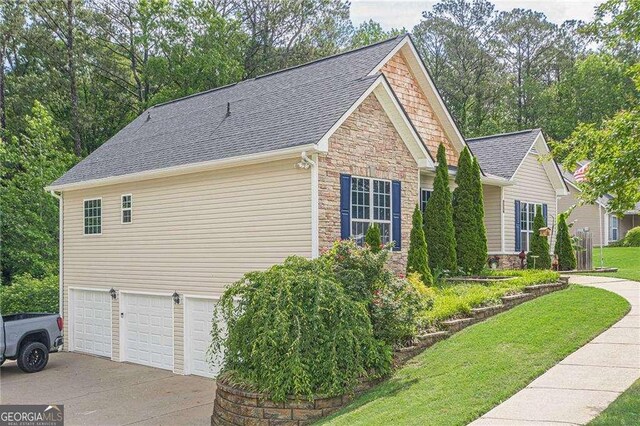 188 Cooper Creek Dr, Dallas, GA 30157 - view of side of property with stone siding, concrete driveway, an attached garage, a yard, and roof with shingles