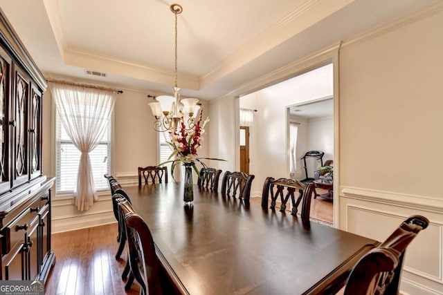 25 Kaktovic Ct, Grayson, GA 30017 - dining room featuring a chandelier, dark wood-style floors, a raised ceiling, ornamental molding, and wainscoting