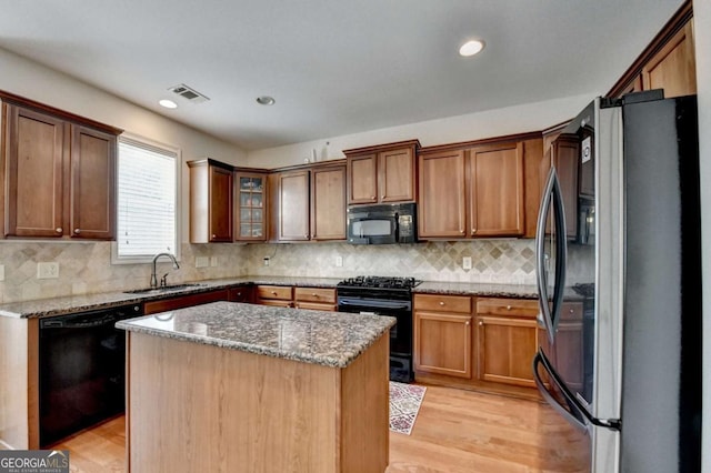 25 Kaktovic Ct, Grayson, GA 30017 - kitchen featuring black appliances, a sink, light stone countertops, light wood-style flooring, and a kitchen island
