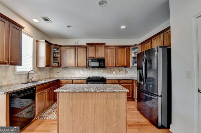 25 Kaktovic Ct, Grayson, GA 30017 - kitchen with black appliances, a sink, light stone counters, a kitchen island, and brown cabinets