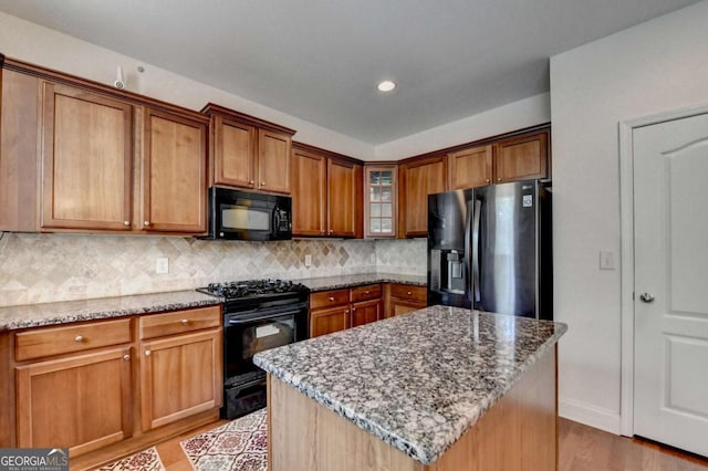 25 Kaktovic Ct, Grayson, GA 30017 - kitchen with black appliances, light wood finished floors, light stone countertops, decorative backsplash, and brown cabinets