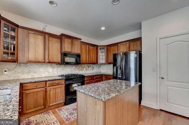 25 Kaktovic Ct, Grayson, GA 30017 - kitchen with black appliances, light wood-style flooring, light stone counters, decorative backsplash, and brown cabinetry