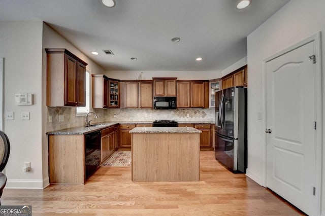 25 Kaktovic Ct, Grayson, GA 30017 - kitchen with black appliances, light stone counters, a center island, light wood-type flooring, and decorative backsplash