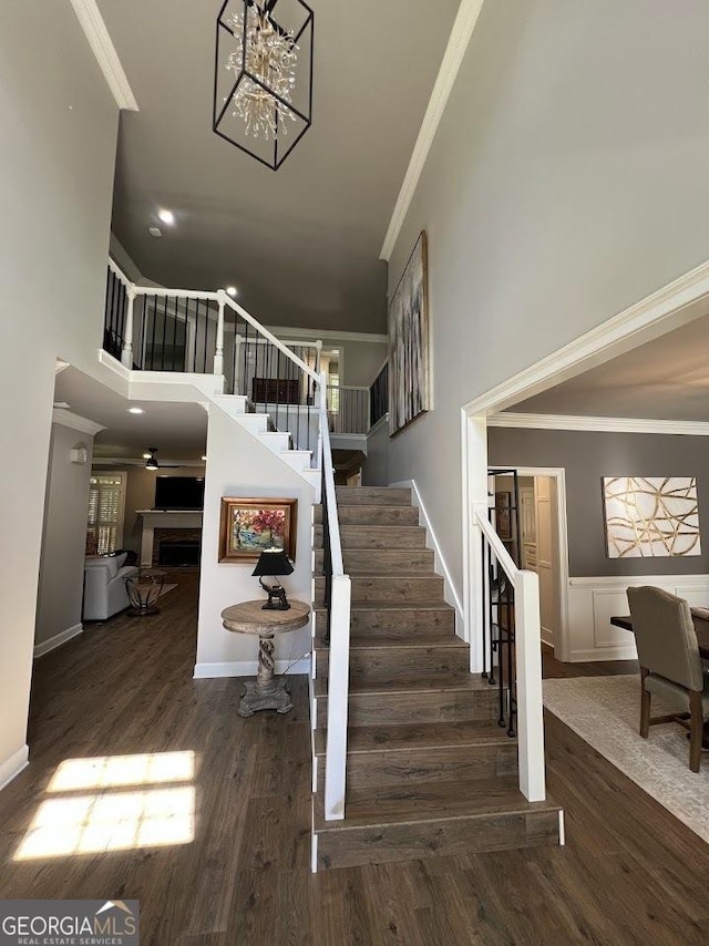 1122 Montclair Dr, Peachtree City, GA 30269 - stairway with ornamental molding, wood finished floors, a high ceiling, a chandelier, and a fireplace