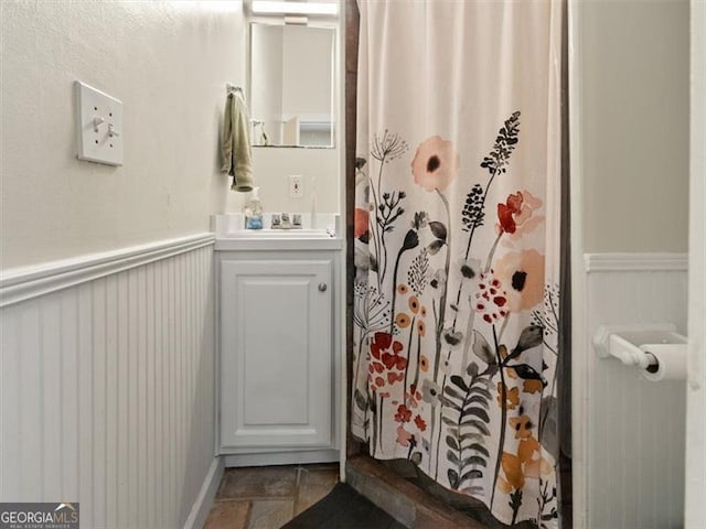 760 Ashland Ave, Atlanta, GA 30307 - bathroom featuring stone finish floors, vanity, a shower with shower curtain, and a wainscoted wall