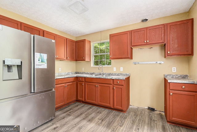 1576 King Mill Rd, Mcdonough, GA 30252 - kitchen featuring stainless steel fridge, light wood-style floors, a textured ceiling, light countertops, and brown cabinets