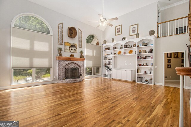 3780 Lovers Ln, Monroe, GA 30656 - unfurnished living room with a ceiling fan, wood finished floors, a fireplace, a towering ceiling, and baseboards