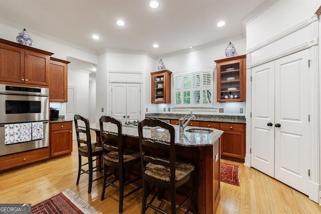 4470 Crestwicke Pointe, Atlanta, GA 30319 - kitchen with double oven, a kitchen bar, a sink, dark stone countertops, and glass insert cabinets