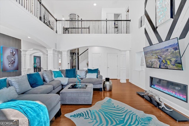 138 Lakestone Pkwy, Woodstock, GA 30188 - living room featuring ornate columns, arched walkways, a high ceiling, wood finished floors, and stairs