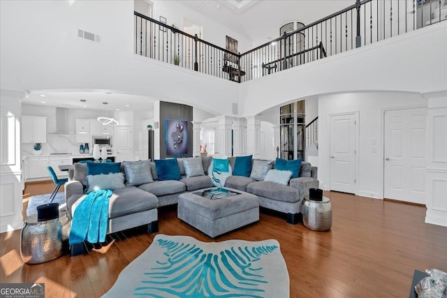 138 Lakestone Pkwy, Woodstock, GA 30188 - living room with ornate columns, arched walkways, dark wood finished floors, and a towering ceiling