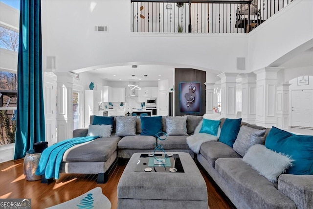 138 Lakestone Pkwy, Woodstock, GA 30188 - living room featuring a towering ceiling, ornate columns, arched walkways, and dark wood-type flooring