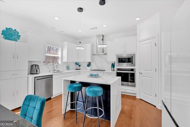 138 Lakestone Pkwy, Woodstock, GA 30188 - kitchen featuring stainless steel appliances, wall chimney exhaust hood, a sink, a kitchen bar, and white cabinets