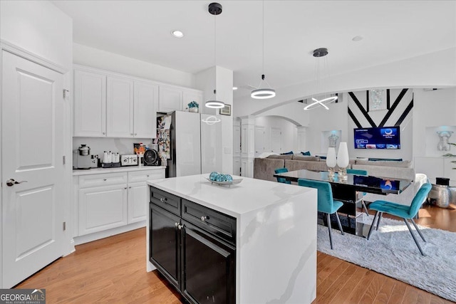 138 Lakestone Pkwy, Woodstock, GA 30188 - kitchen with decorative columns, open floor plan, white cabinetry, arched walkways, and freestanding refrigerator