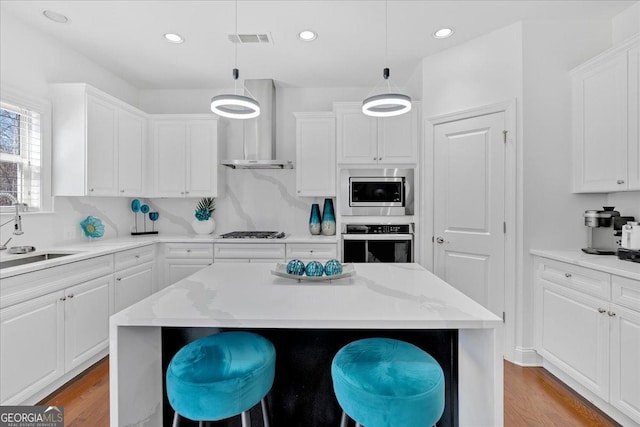 138 Lakestone Pkwy, Woodstock, GA 30188 - kitchen with appliances with stainless steel finishes, wall chimney exhaust hood, a sink, white cabinetry, and light wood finished floors