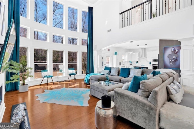 138 Lakestone Pkwy, Woodstock, GA 30188 - living room with ornate columns, a towering ceiling, arched walkways, plenty of natural light, and wood finished floors