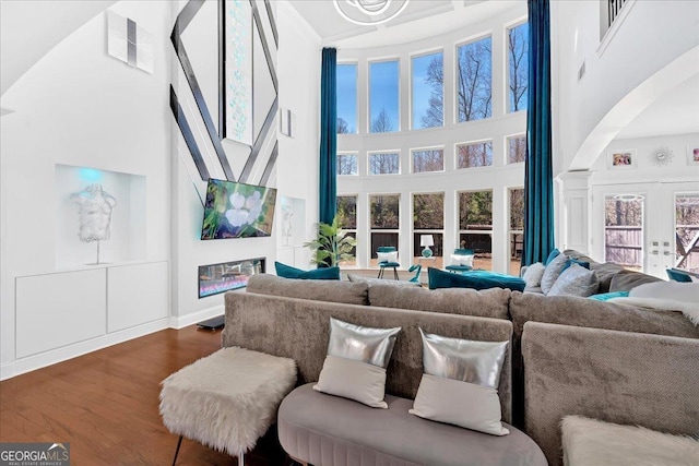 138 Lakestone Pkwy, Woodstock, GA 30188 - living area with a towering ceiling, arched walkways, dark wood-type flooring, french doors, and baseboards
