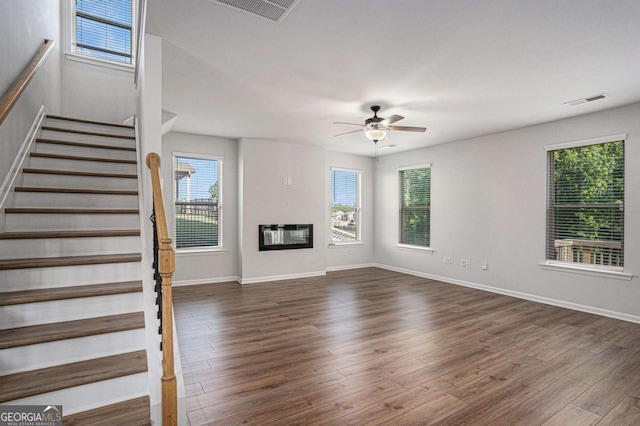 953 Mystic Way, Hampton, GA 30228 - unfurnished living room with ceiling fan, dark wood-style flooring, stairs, and a glass covered fireplace