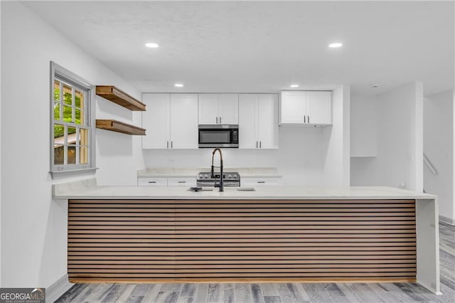 5200 Beechwood Forest Ct, Lithonia, GA 30038 - kitchen with stainless steel microwave, open shelves, white cabinets, a peninsula, and recessed lighting
