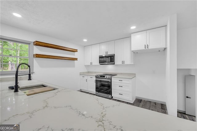 kitchen featuring stainless steel appliances, open shelves, a sink, white cabinets, and recessed lighting