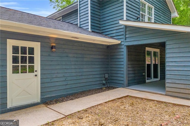 doorway to property with a shingled roof