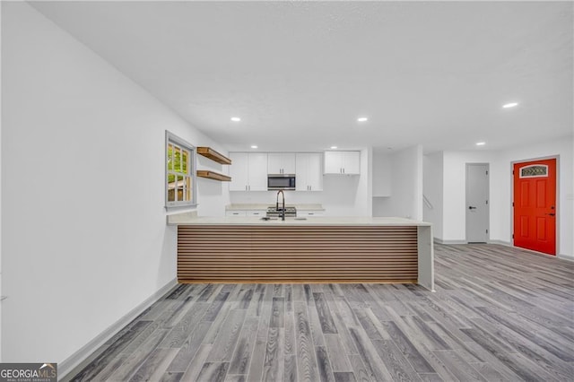 5200 Beechwood Forest Ct, Lithonia, GA 30038 - kitchen with stainless steel microwave, light countertops, recessed lighting, light wood-style flooring, and white cabinetry
