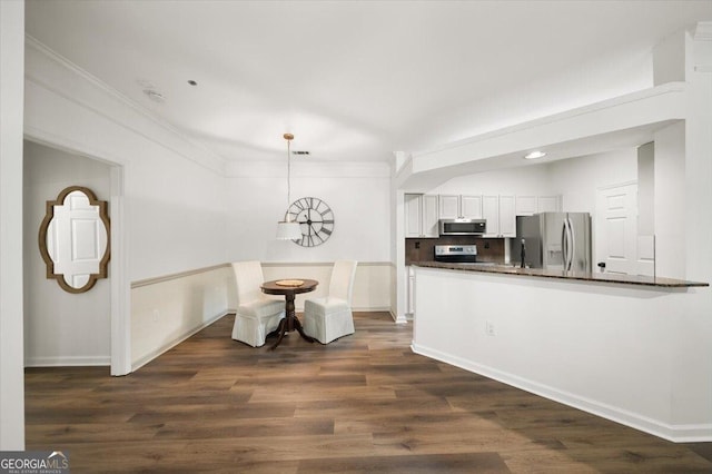 kitchen featuring appliances with stainless steel finishes, dark countertops, white cabinets, baseboards, and ornamental molding