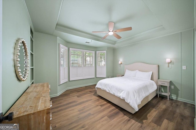 bedroom with a raised ceiling, ornamental molding, wood finished floors, baseboards, and ceiling fan