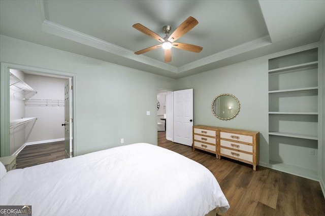 bedroom featuring a tray ceiling, ornamental molding, wood finished floors, and a ceiling fan