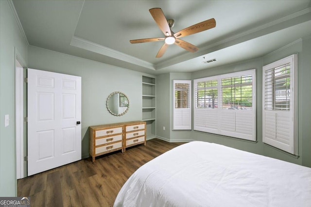 bedroom featuring crown molding, wood finished floors, baseboards, a tray ceiling, and ceiling fan