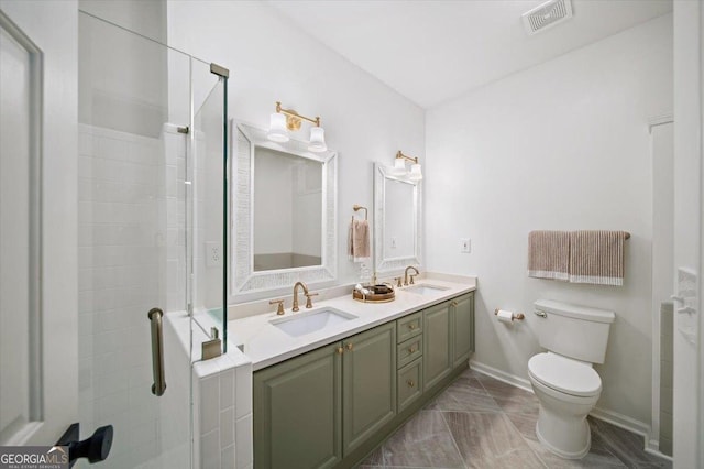 bathroom featuring toilet, a stall shower, double vanity, and marble finish floors