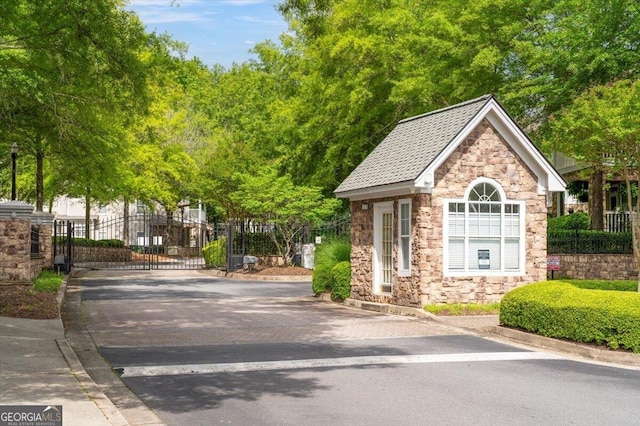 view of front of home with stone siding, a gate, fence, and driveway