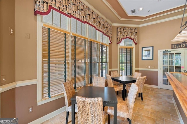 dining room with baseboards, ornamental molding, a high ceiling, and light stone finish floors