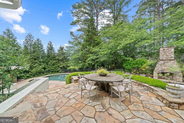 143 Wildwood Dr, Eatonton, GA 31024 - view of patio featuring an outdoor stone fireplace, an outdoor pool, fence, outdoor dining space, and view of scattered trees
