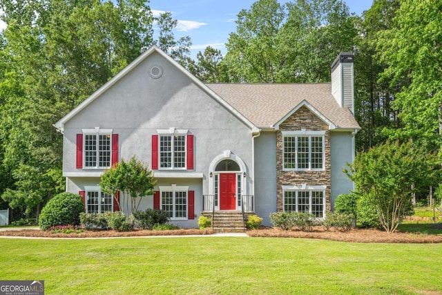 split foyer home with stone siding, a front lawn, a chimney, stucco siding, and a shingled roof