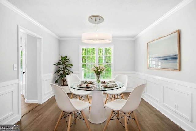 dining area with dark wood-style floors, ornamental molding, a wainscoted wall, and a decorative wall
