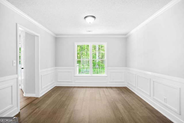 spare room with dark wood-type flooring, a wainscoted wall, ornamental molding, and a textured ceiling
