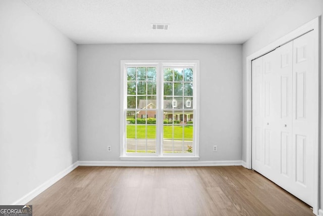 unfurnished bedroom with wood finished floors, a closet, baseboards, and a textured ceiling