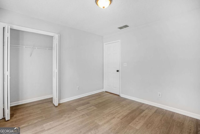 unfurnished bedroom featuring wood finished floors, a closet, and baseboards
