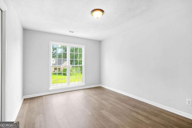 spare room featuring wood finished floors, a textured ceiling, and baseboards