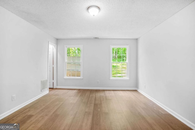 spare room featuring wood finished floors, a textured ceiling, and baseboards