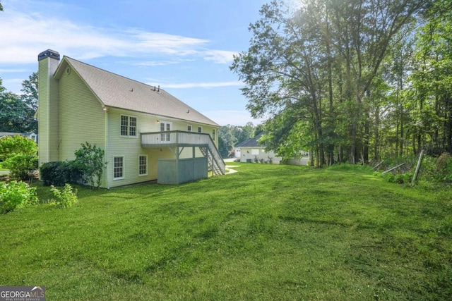 rear view of property with a chimney, stairway, and a yard