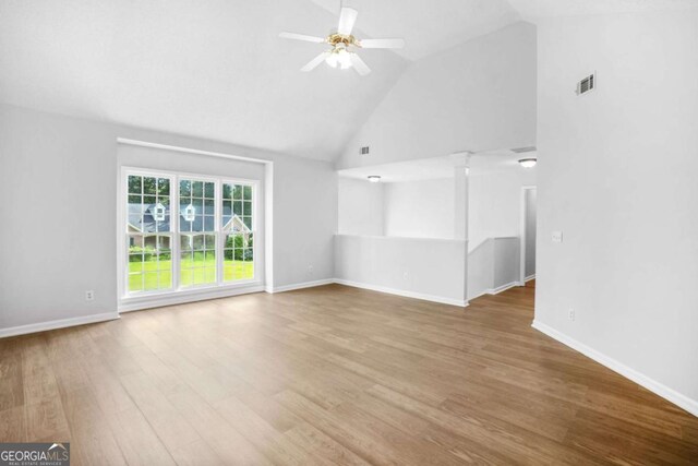 unfurnished living room with high vaulted ceiling, wood finished floors, a ceiling fan, and baseboards