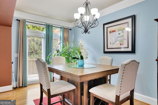 dining area with a chandelier, light wood finished floors, baseboards, and ornamental molding