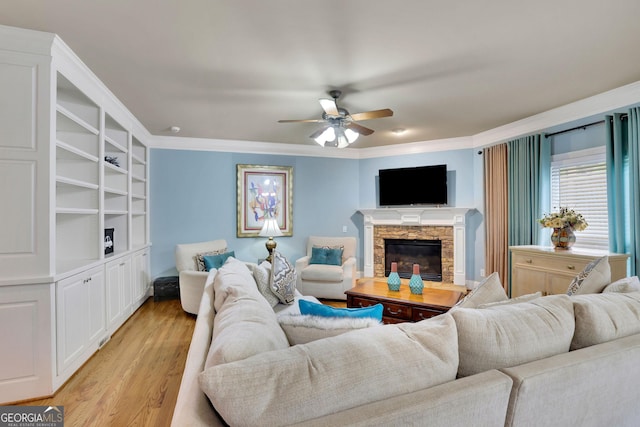 living area featuring ceiling fan, light wood-type flooring, a fireplace, and crown molding