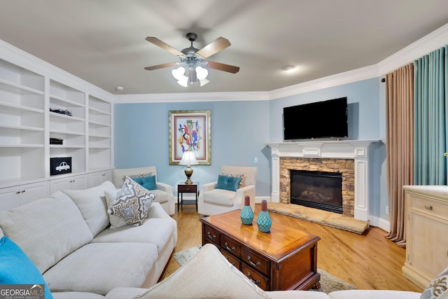 living area with light wood-style flooring, ceiling fan, ornamental molding, baseboards, and a fireplace