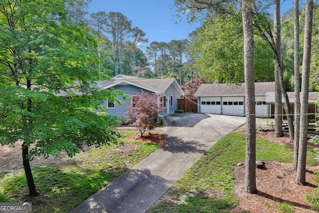 ranch-style home with a garage, an outbuilding, concrete driveway, and fence