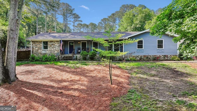 single story home with a porch, fence, and stone siding