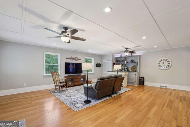 living room with ceiling fan, light wood finished floors, baseboards, and recessed lighting