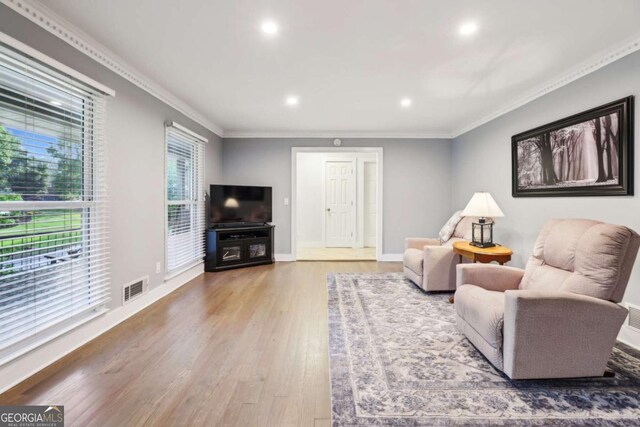 living room with recessed lighting, wood finished floors, ornamental molding, and baseboards